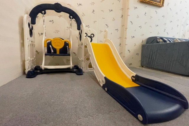 The room has a children's slide and play equipment.